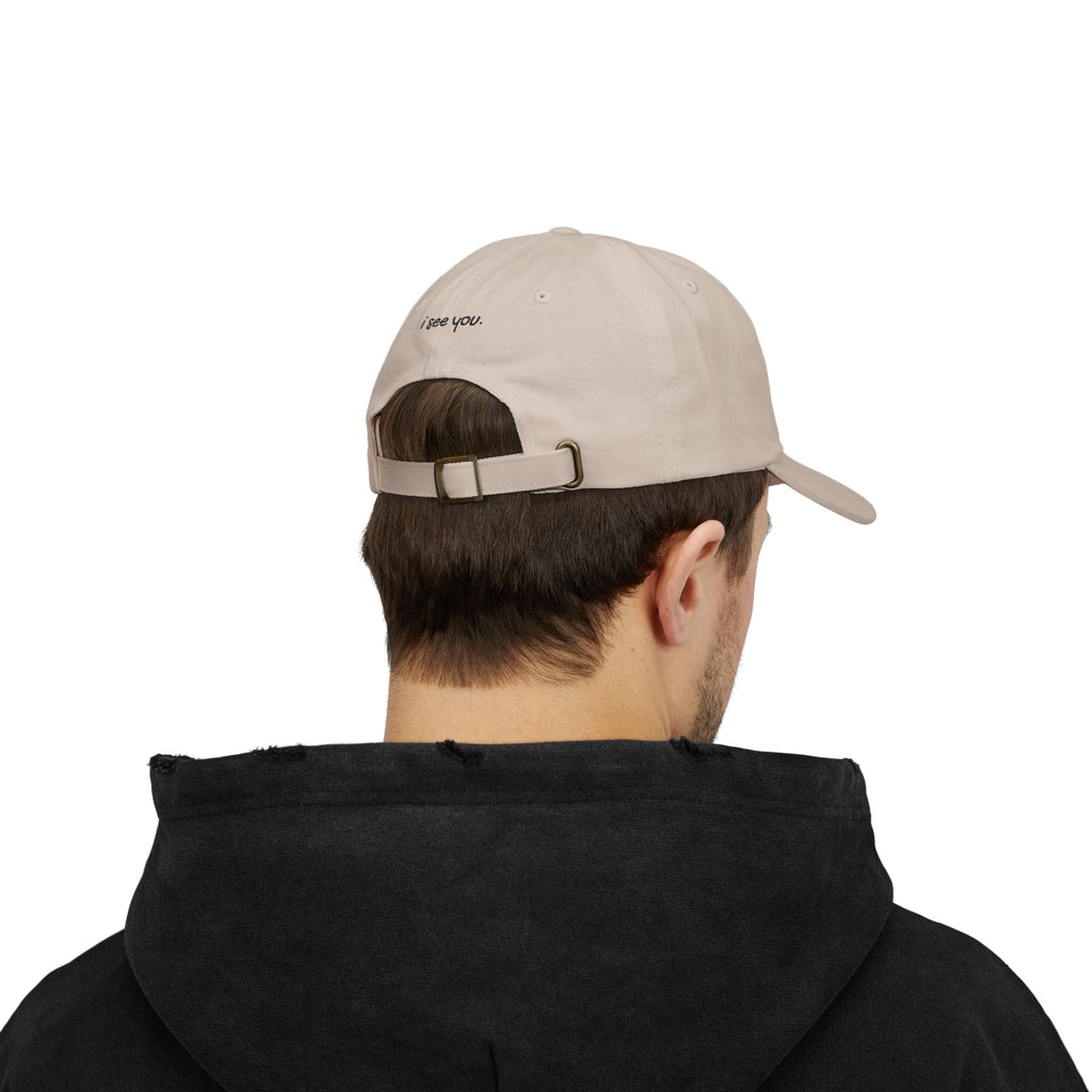 TUCURUCU beige cotton cap worn backwards, featuring i see you embroidery above the antique brass adjustable strap.
