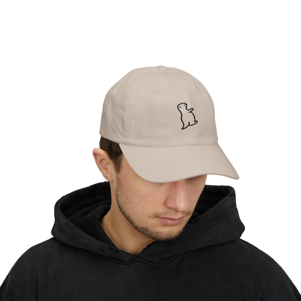 TUCURUCU beige 6-panel cotton cap with a small embroidered character on the front, worn by a man in a black hoodie.